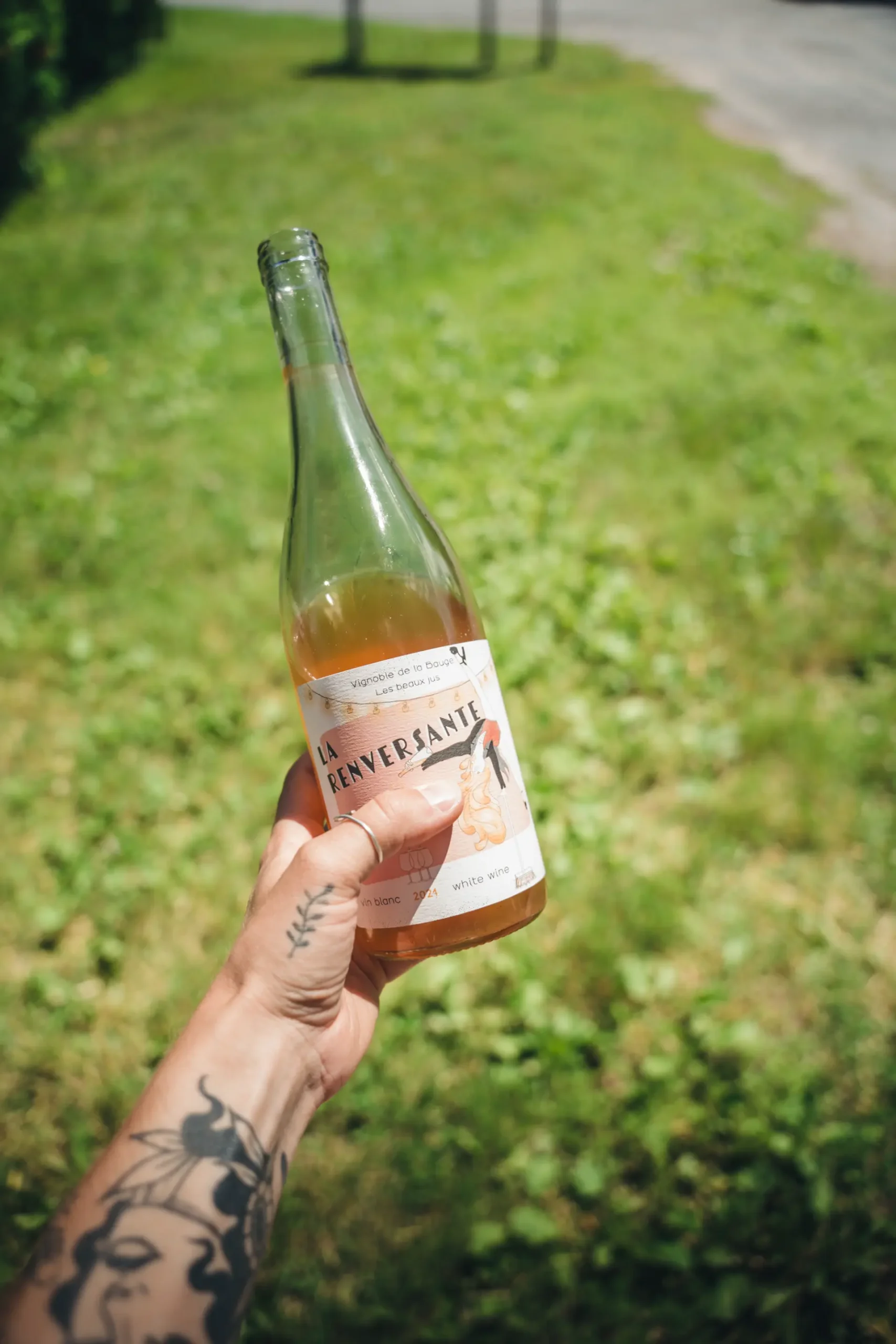 bouteille vin blanc route vins brome missisquoi scaled Une main tient une bouteille de vin blanc La Renversante, du vignoble de La Bauge, sur La Route des vins de Brome-Missisquoi, Cantons-de-l'Est.