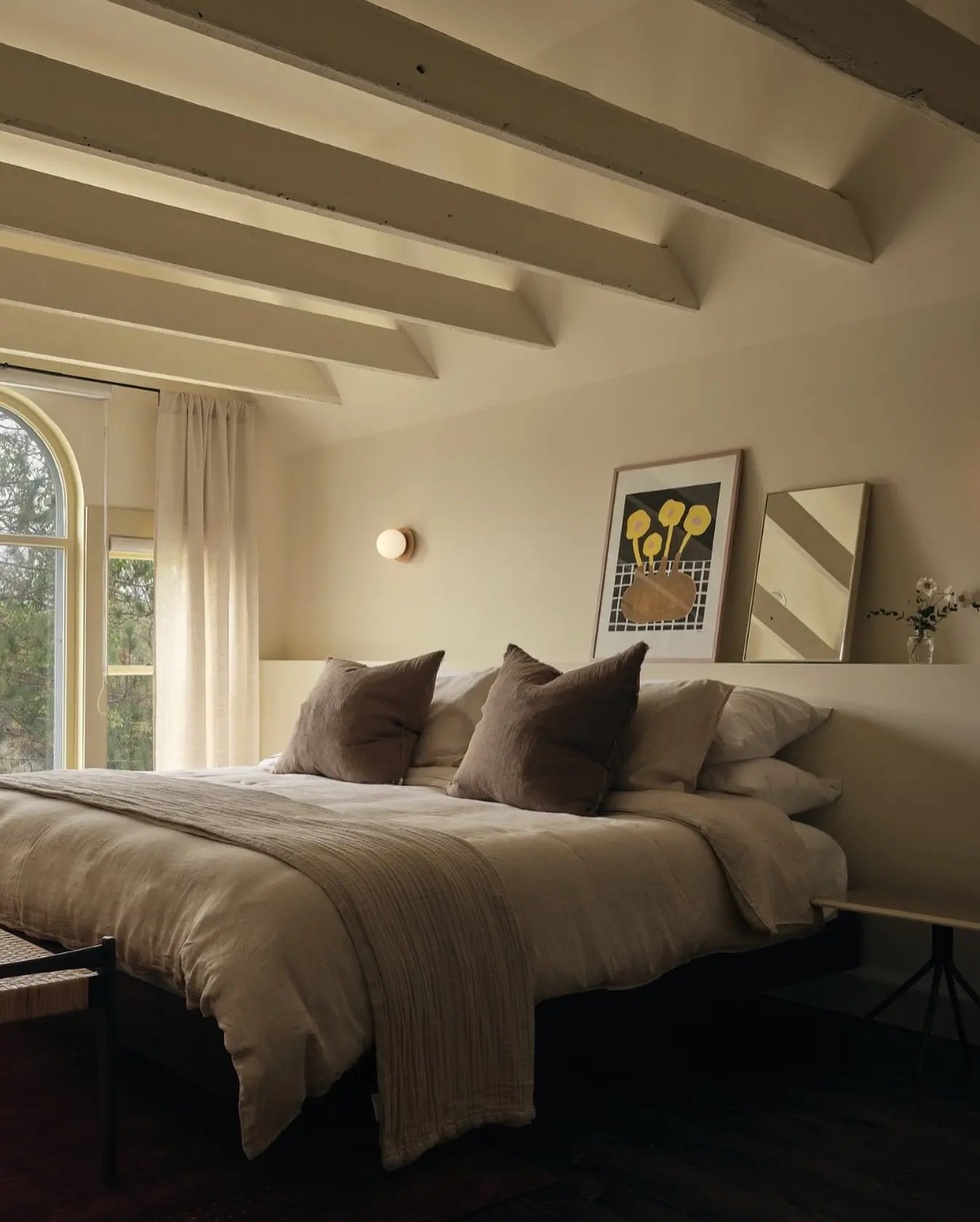 chambre confortable route des vins brome missisquoi Chambre du Pinôt Boutique Hôtel, avec grand lit, literie beige, coussins marron, poutres apparentes, sur La Route des vins Brome-Missisquoi.